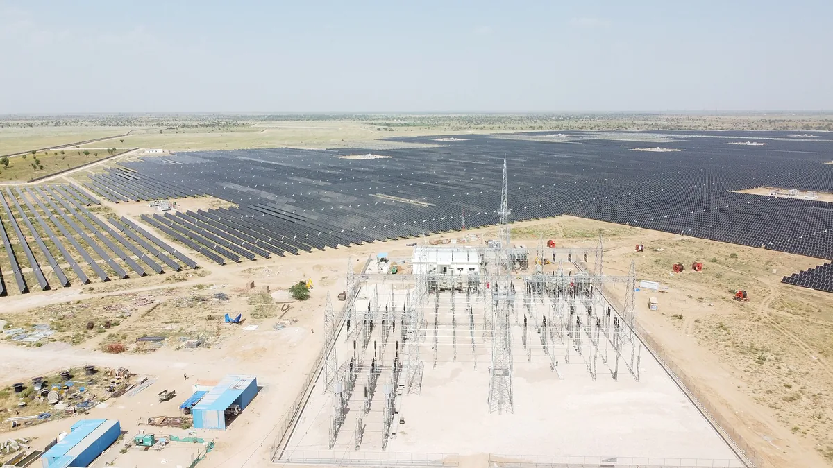 Aerial view of rows of solar panels and a substation at Bhadla Solar Park, Rajasthan